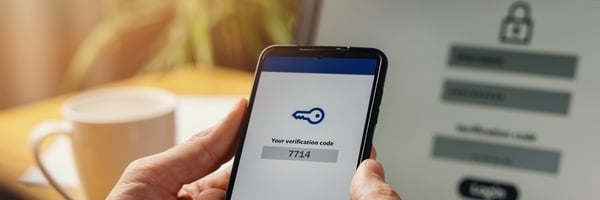 Auf einem Handy erscheint der Schlüssel zur Multi-Faktor-Authentifizierung auf dem Laptop