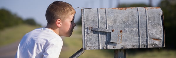 Ein Junge schaut in einen leeren Briefkasten