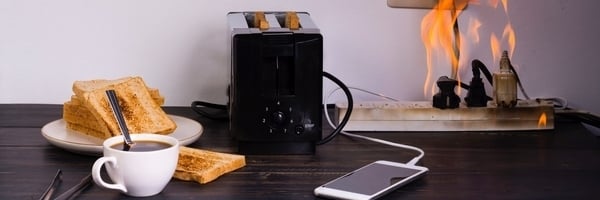 Man sieht eine Küche mit Toaster, Kaffeetasse und einer brennenden Steckdosenleiste